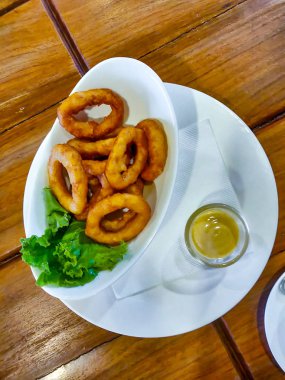 Soğan halkaları beyaz bir tabakta servis edilir. Üstte görüntü