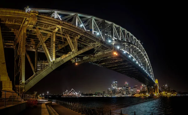 Lado este del puente del puerto de Sydney en nihgt con reflejo brillante en las aguas borrosas del puerto — Foto de Stock
