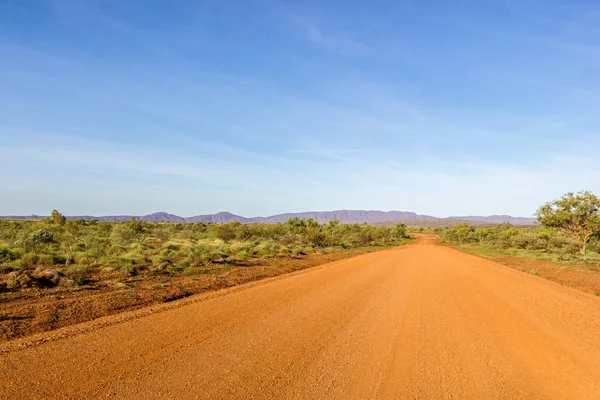 Czerwone australijskie wiejskiej drodze z zachmurzonego nieba niebieski, Western Australia, Australia — Zdjęcie stockowe