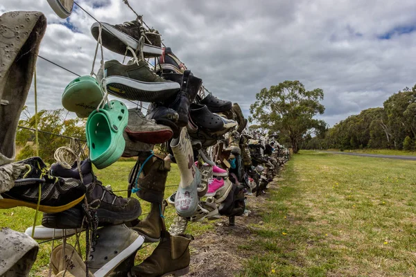Alte schuhe an einem zaun neben einer straße in australien. Touristen stellen ihre alten Schuhe an den Zaun — Stockfoto