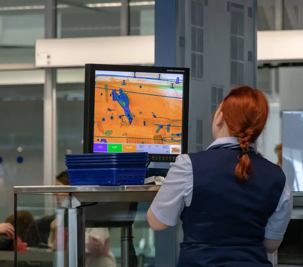 Havaalanı, Münih, Almanya, 2019 Nisan 09: Üniformalı kadınlar kontrol noktasında durup bavullarının röntgenlerini izliyorlar..