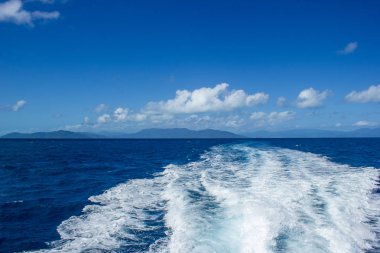 beautiful wake wave behind a big boat for tourist diving at the great barrier reef with blue montains in the background, cairns, australia