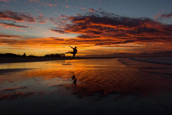 Silhouette of a young man jumping on the beach in nelson during sunset on Tahunanui Beach at Nelson, New Zealand — Stock Photo, Image