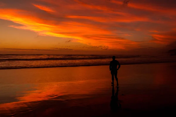 Young man walking outdoors watching the sunset at a beach. Thinking and relaxing concept. — Stock Photo, Image