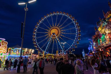 Munich, Germany - 2019, September 24: visitors from all over the world walking in front of the ferris wheel at the Oktoberfest in Munich at night, Bavaria