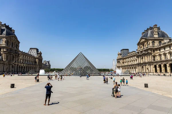Париж, Франция - 27 июня 2019 года: Вид на пирамиду и фонтан во дворе музея Лувра. Лувр музей является одним из крупнейших и самых посещаемых музеев в мире. — стоковое фото