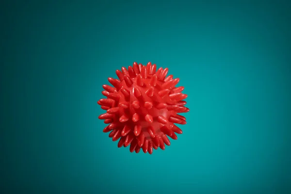 Beautiful red massage ball with spikes for stimulation and circulation, hangs in the air on the ocean background. relaxation, health. Thematic and subject-matter shooting