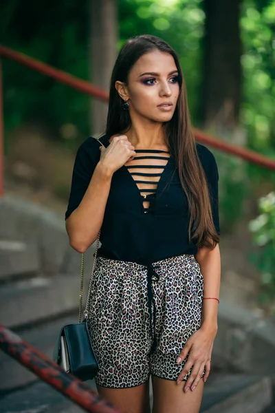 Güzel ve çekici bir kız bir kenara bakar, bir çanta tutar. Kahverengi gözlü, siyah ceketli. Arka planı bir kenara bırak. Yarım boy portre. Seksi bayan..