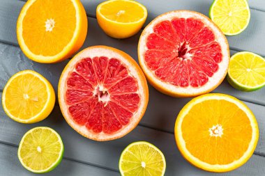 Gri ahşap bir masada sulu portakallar, greyfurtlar, limonlar ve limonlar yatıyor. Yukarıdan bak. Bir sürü narenciye, bir sürü zeka ve kullanışlı amino asit..