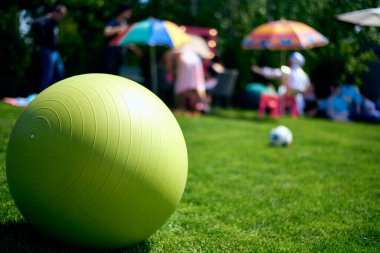 Yeşil büyük lastik top, fitball, yeşil bir çimenlikte yatıyor. Çocuk oyunu. Spor ve aerobik için şenlik havası..