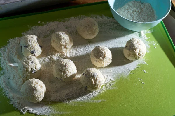 Queijo cottage com passas em farinha, torcido em bolas, e pronto para assar. cheesecakes para crianças. Alimentos saudáveis e nutritivos. Cozinha caseira — Fotografia de Stock