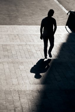 Gözlüklü adamın silueti, beton bir merdivenin tepesine yükseliyor, gölgesinden ilginç bir yansıma yaratıyor. Güneş ışığını kontrol et. Sanat ve sokak fotoğrafçılığı. Güzel çerçeve bileşimi