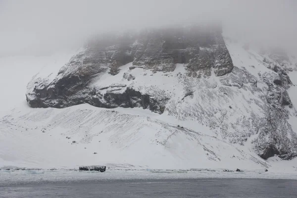 Antarctica landscape with ocean, snow, ice and icebergs on a cloudy day