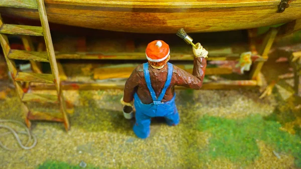 Miniature mini figure worker painting a boat at dock diorama