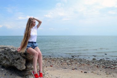 Deniz kenarında rahatlatıcı beyaz t-shirt genç kadın