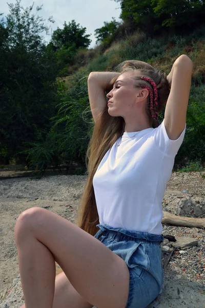 Ung kvinna i vit t-shirt avslappnande i naturen — Stockfoto