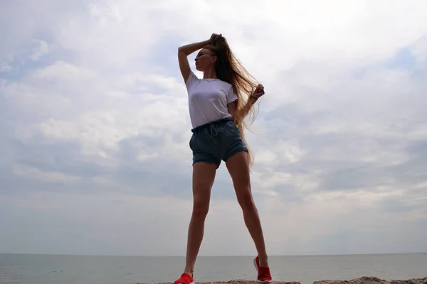 Junge Frau im weißen T-Shirt entspannt am Meer — Stockfoto