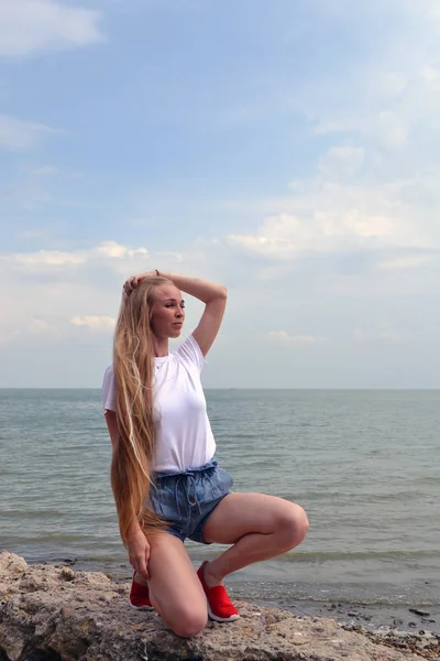 Mladá žena v bílém tričku relaxačně u moře — Stock fotografie
