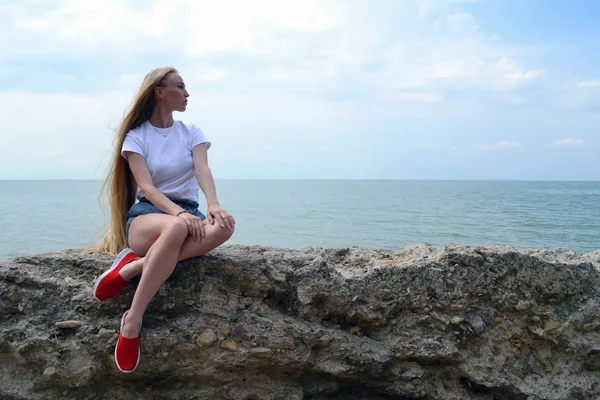 Ung kvinna i vit t-shirt avkopplande vid havet — Stockfoto