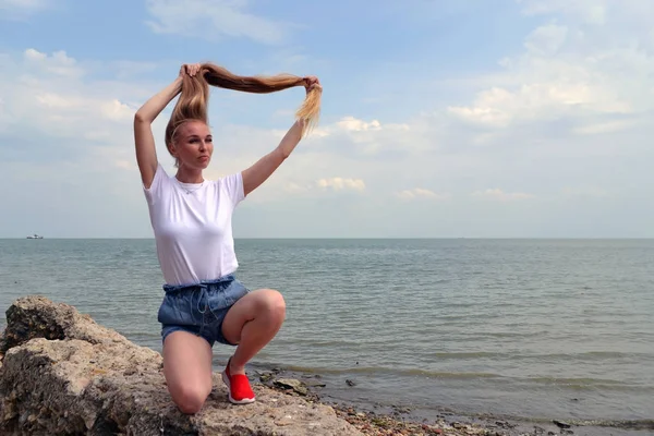 Fiatal nő, fehér póló pihentető a tenger Jogdíjmentes Stock Fotók