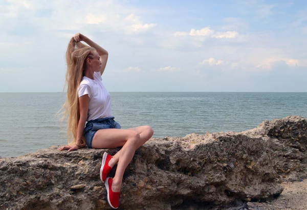 Junge Frau im weißen T-Shirt entspannt am Meer Stockfoto