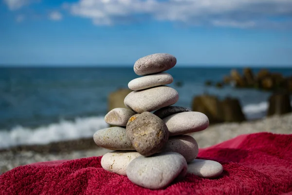 Kamienie ułożone piramidy na plaży z błękitne niebo i morze. — Zdjęcie stockowe