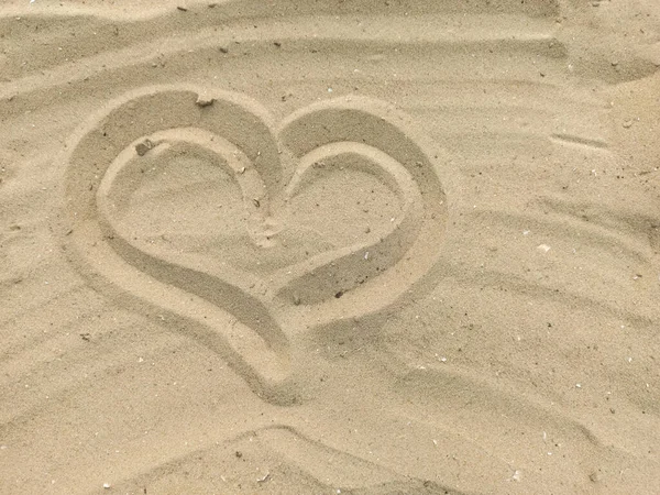 Heart drawn in the sand. Beach background. Top view