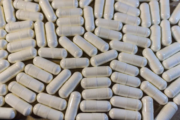 A handful of white pills close-up. Capsules medication is white.