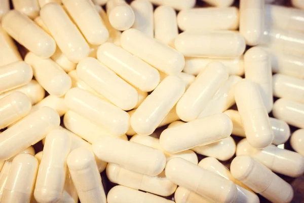 A handful of white pills close-up. Capsules medication is white.