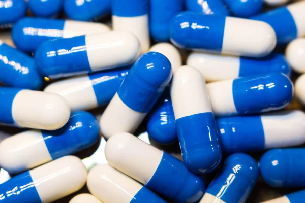 Um punhado de comprimidos de perto. Cápsulas medicamentos branco e azul . — Fotografia de Stock