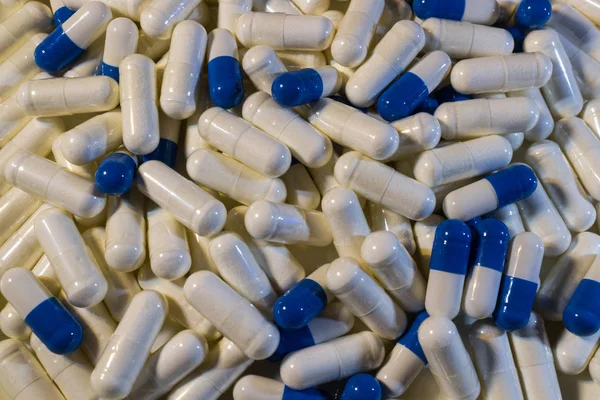 Una manciata di pillole bianche e blu da vicino. Capsule farmaci bianchi e blu . — Foto Stock