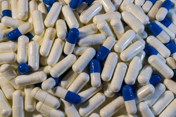 Una manciata di pillole bianche e blu da vicino. Capsule farmaci bianchi e blu . — Foto Stock