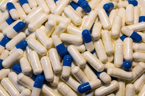 Una manciata di pillole bianche e blu da vicino. Capsule farmaci bianchi e blu . — Foto Stock