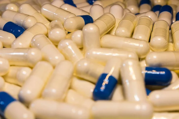 Um punhado de comprimidos brancos e azuis de perto. Cápsulas medicamentos branco e azul . — Fotografia de Stock