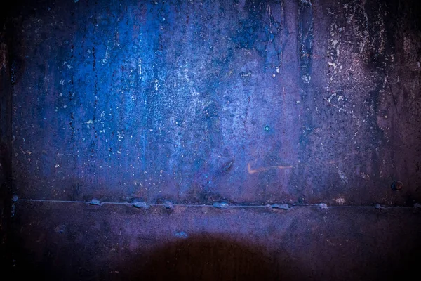 Rusty iron garage wall with a welding line. Bolts