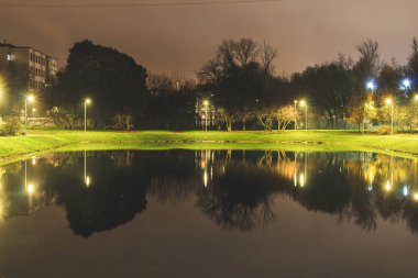 Aydınlatma ışık yansıması ile RADIUS çevresinde şehir gölet. Akşam saat.