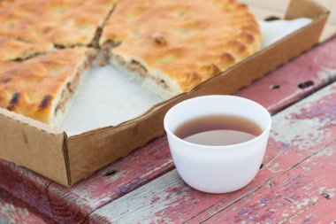 Etli börek bir bankta bir kupa çay yanında