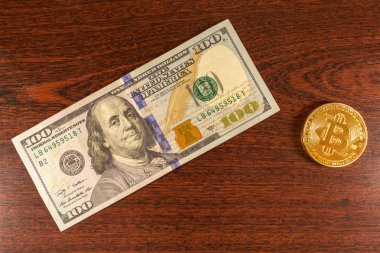 Bitcoin madeni para üzerinde 100 bir banknot yatıyor