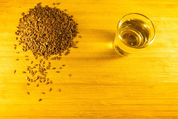 Flax seed handful, flaxseed oil in a glass on the table