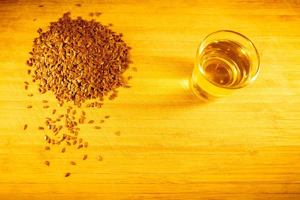 Flax seed handful, flaxseed oil in a glass on the table