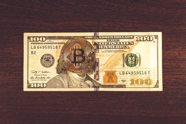 Bitcoin madeni para üzerinde 100 bir banknot yatıyor