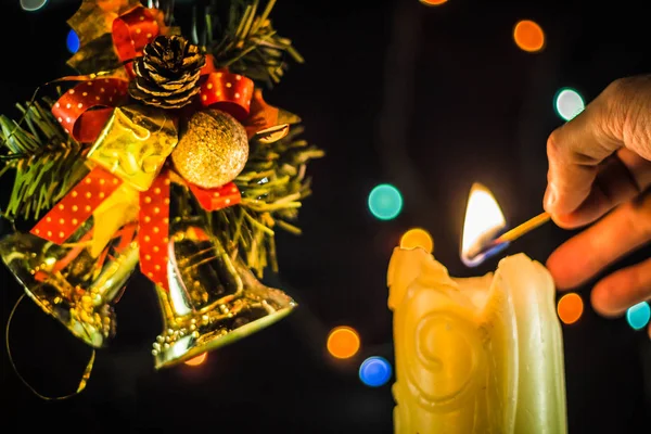 Блестящая Свеча Зажигает Руку Спичкой Возле Ветвей Рождественских Колоколов — стоковое фото
