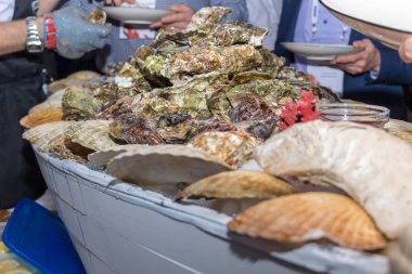 Bir adam demir eldiven ziyaret tabaklarda istiridye sunar