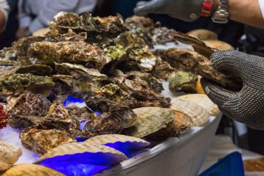 Bir adam istiridye kabukları ile demir eldiven içinde temizler. Kurumsal