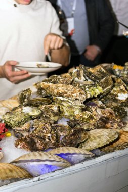 Bir adam demir eldiven ziyaret tabaklarda istiridye sunar