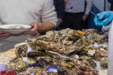 Bir adam demir eldiven ziyaret tabaklarda istiridye sunar