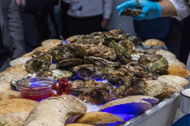 Bir adam demir eldiven ziyaret tabaklarda istiridye sunar