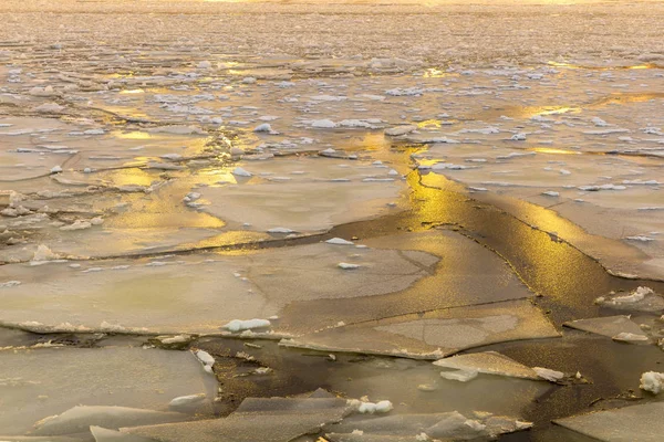 Cracked ice on the river. Spring warming, melting ice. Evening time