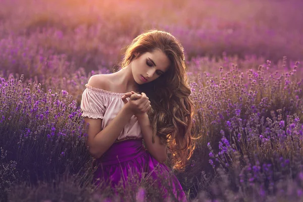 Uma jovem mulher num campo de lavanda ao pôr-do-sol. Retrato de uma bela menina sensual em flores de lavanda . — Fotografia de Stock