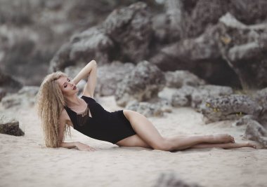 Güzel sarışın kum kayalık bir plajda yatan... Yaz plaj kavramı. Seksi yaz kadın vücut.